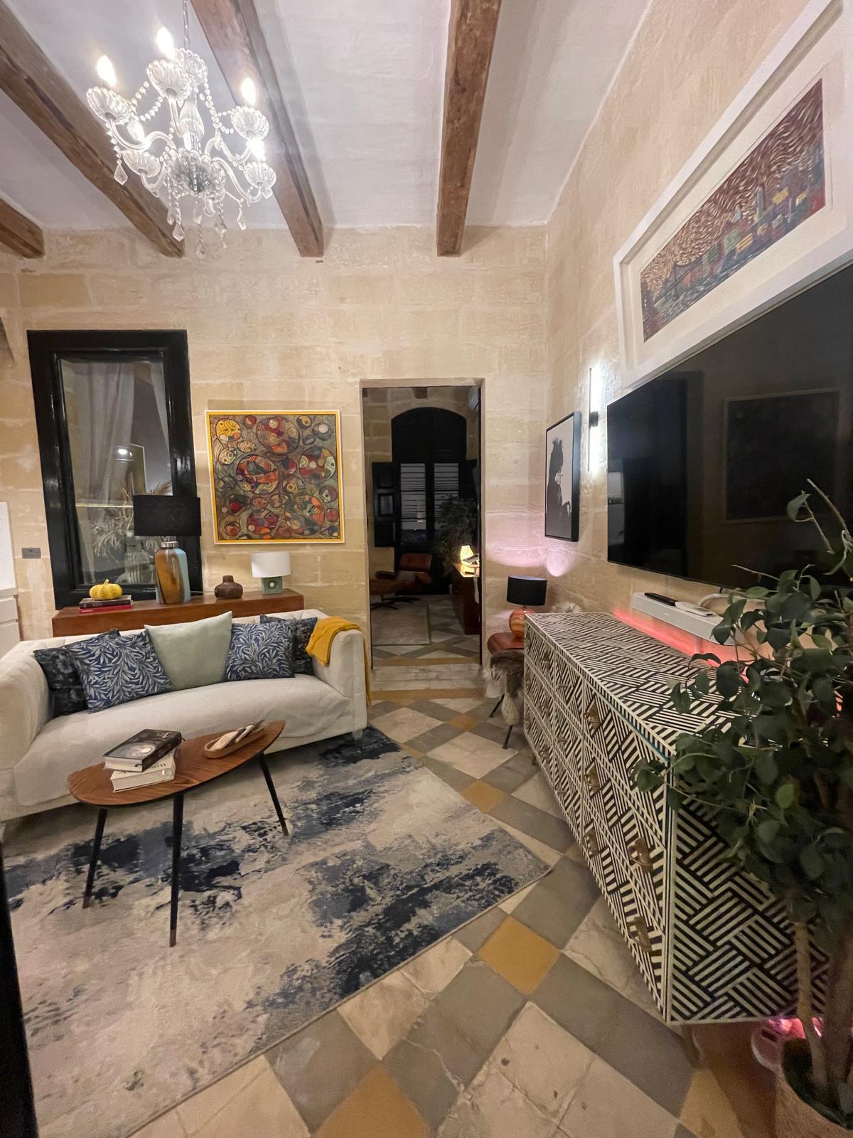 The lounge in portrait view: chandelier, sofa, and the fish painting above.